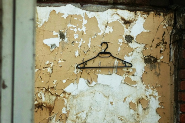 Un mur avec du papier déchiré et un cintre pour symboliser les vies antérieures